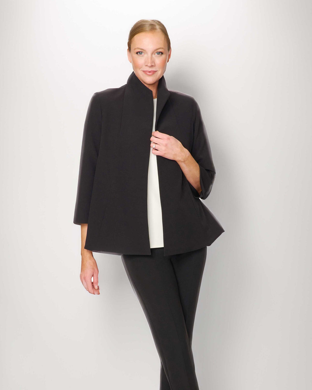 Woman wearing a black coat and pants on a white background